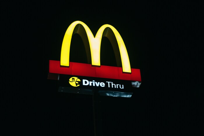 Placa iluminada do McDonald’s no período noturno exibindo os arcos dourados em destaque, reforçando a repetição visual que fortalece o reconhecimento de marca e a identidade visual da empresa; exemplo clássico do efeito da mera exposição aplicado à comunicação estratégica para consolidar uma marca forte e memorável.
