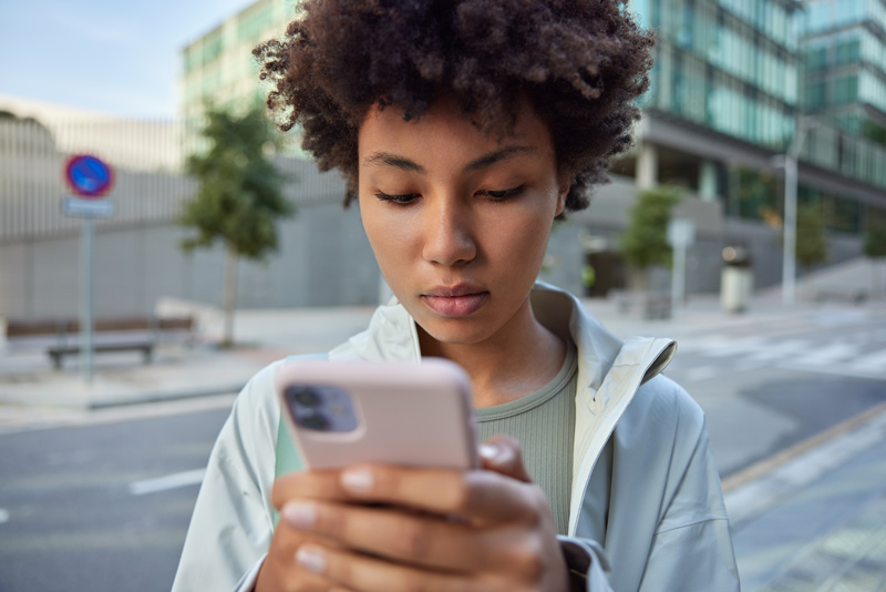 Jovem usando smartphone, representando o consumo de mídia digital.